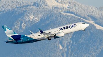 WestJet Boeing aircraft taking off with snowy mountains behind