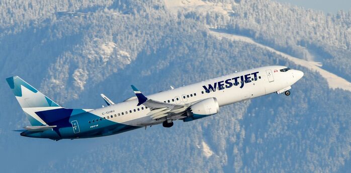 WestJet Boeing aircraft taking off with snowy mountains behind