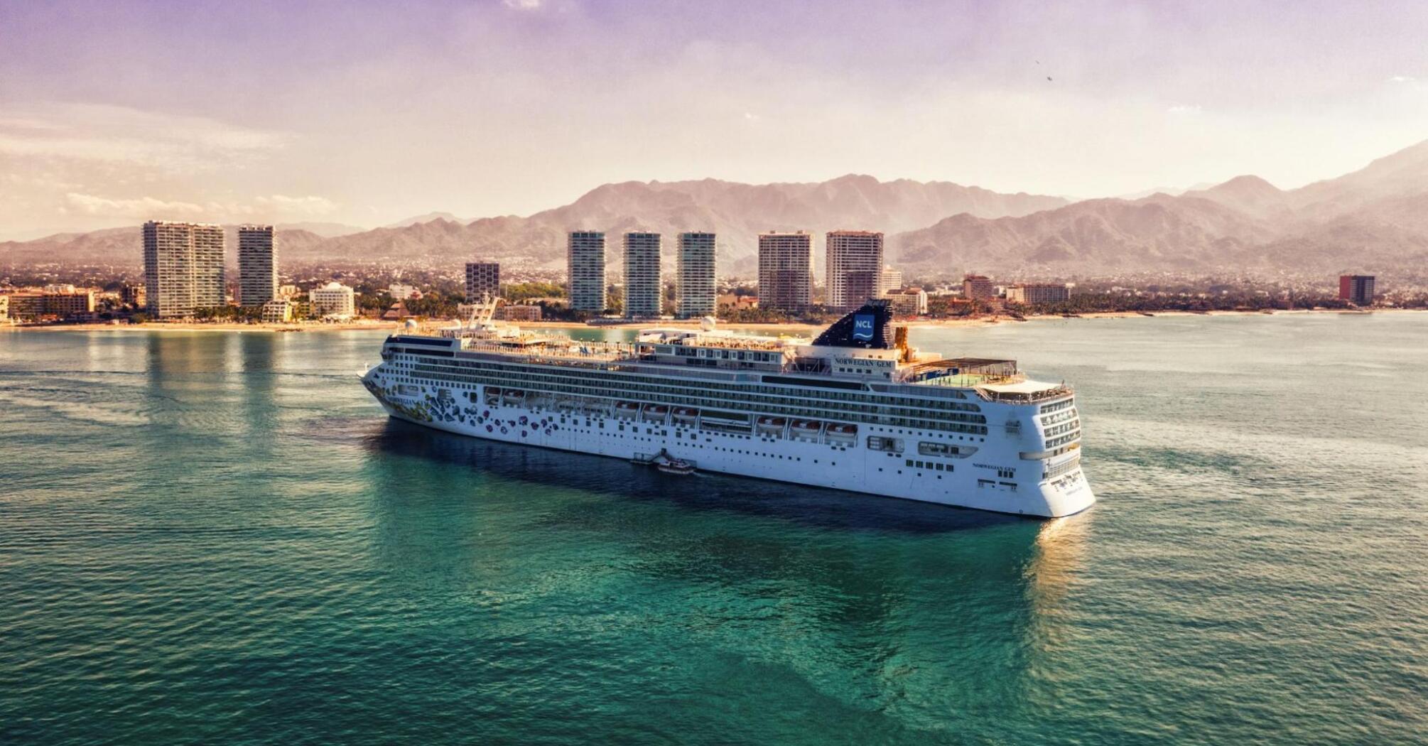 Norwegian Cruise Line ship sailing near a coastal city