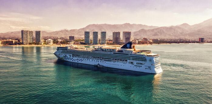 Norwegian Cruise Line ship sailing near a coastal city