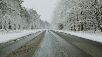 Snow-covered rural road surrounded by frosty trees