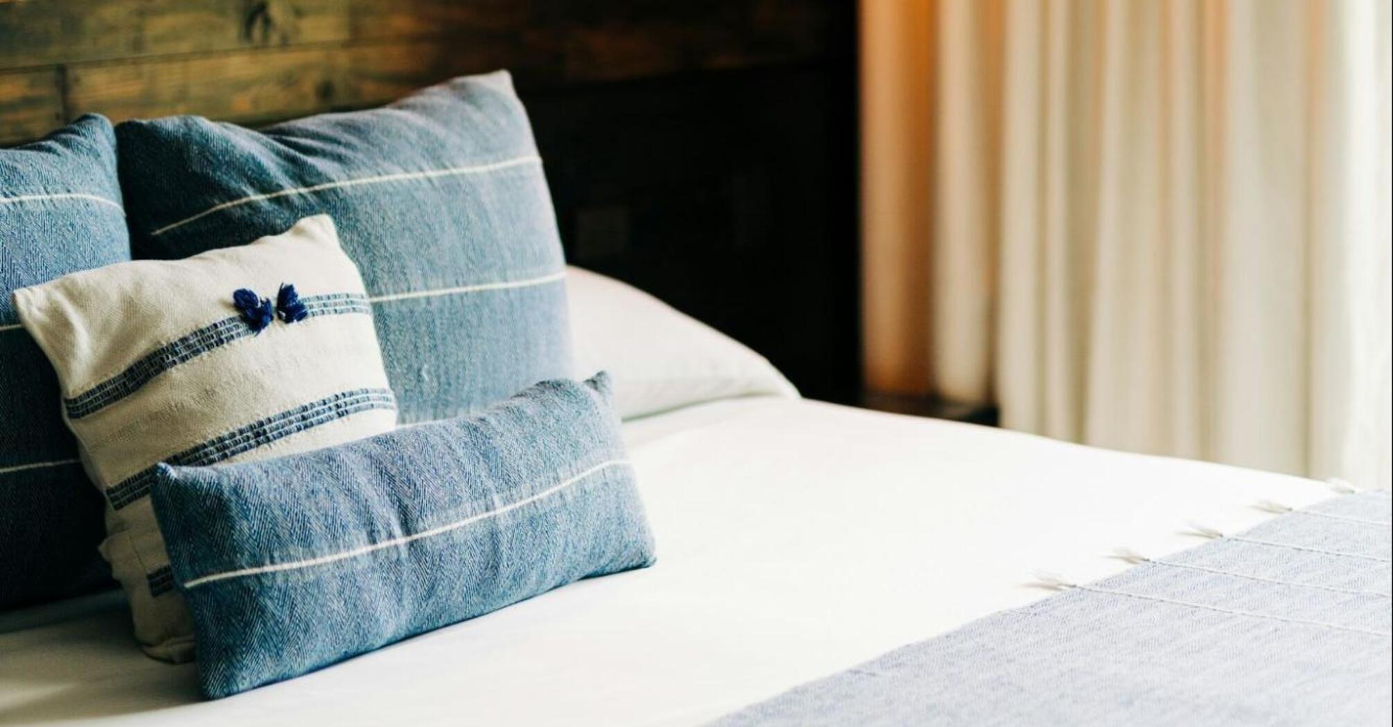 A neatly arranged hotel room with soft lighting and blue-toned bedding