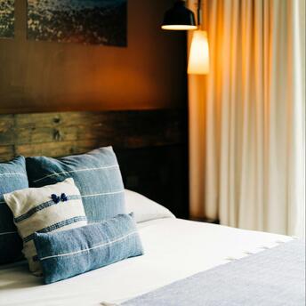 A neatly arranged hotel room with soft lighting and blue-toned bedding