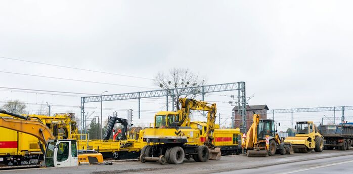 Rail engineering vehicles and machinery parked along a rail line during maintenance work
