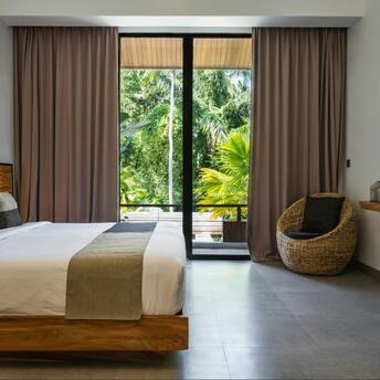 Modern hotel room with large windows overlooking tropical greenery