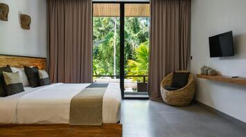 Modern hotel room with large windows overlooking tropical greenery