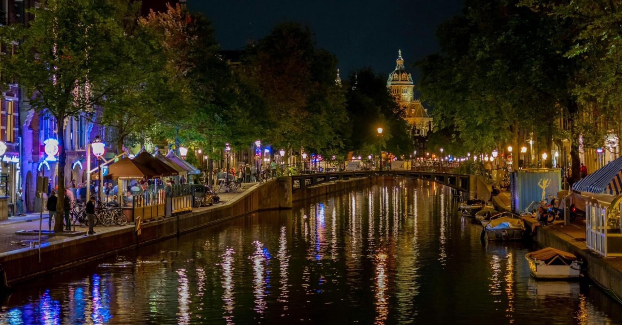 Night view of illuminated Amsterdam canal with reflections on the water