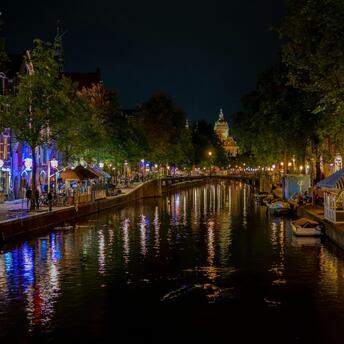 Night view of illuminated Amsterdam canal with reflections on the water