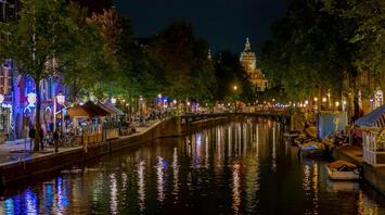 Night view of illuminated Amsterdam canal with reflections on the water