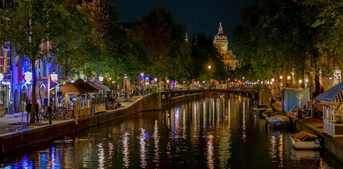 Night view of illuminated Amsterdam canal with reflections on the water