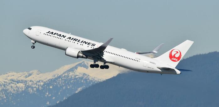 Japan Airlines aircraft taking off with snowy mountains in the background