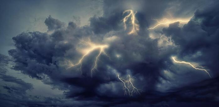 Dark storm clouds illuminated by multiple lightning strikes