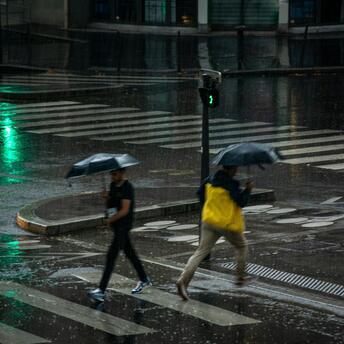 People crossing a city street under umbrellas during heavy rain
