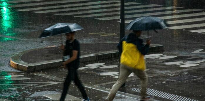 People crossing a city street under umbrellas during heavy rain