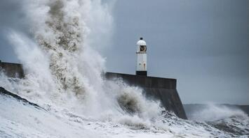 Large waves crashing against a coastal breakwater during stormy weather