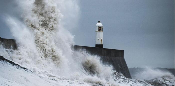 Large waves crashing against a coastal breakwater during stormy weather