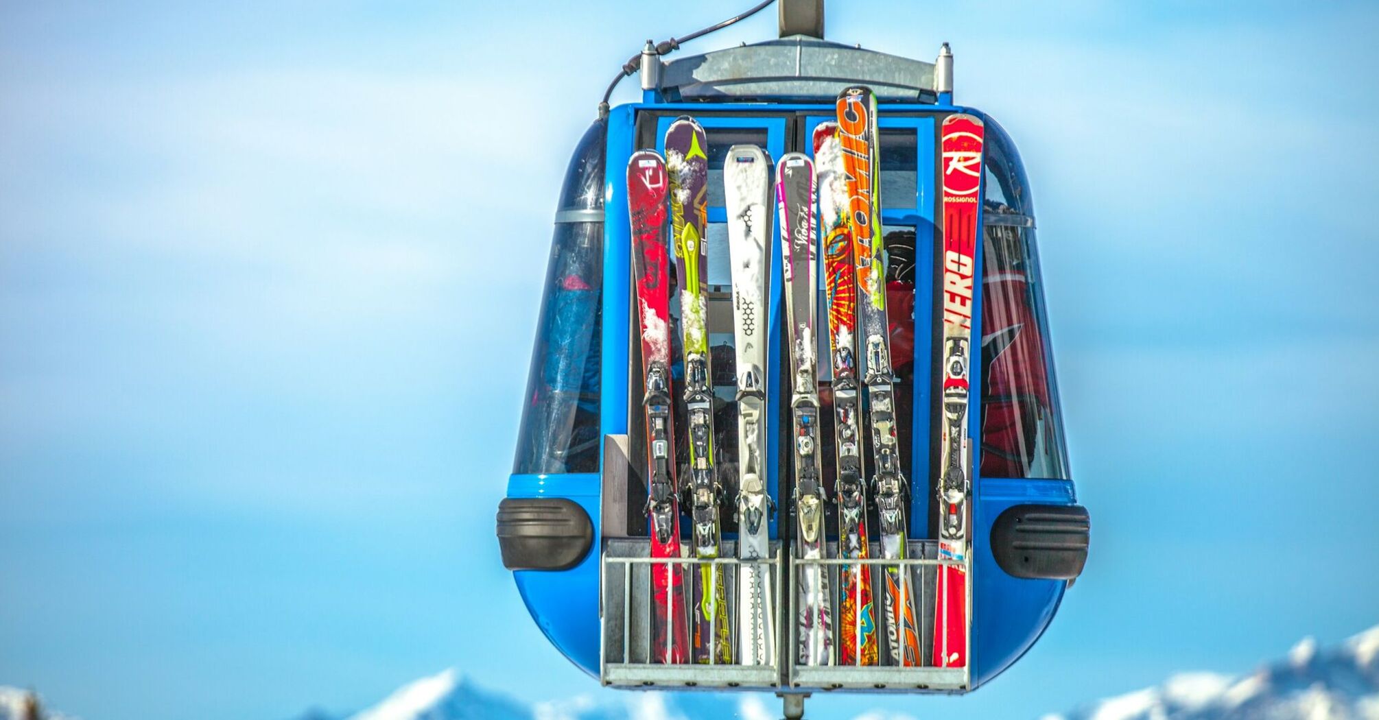 Ski gondola carrying skis with mountain peaks behind