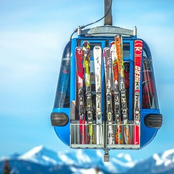 Ski gondola carrying skis with mountain peaks behind