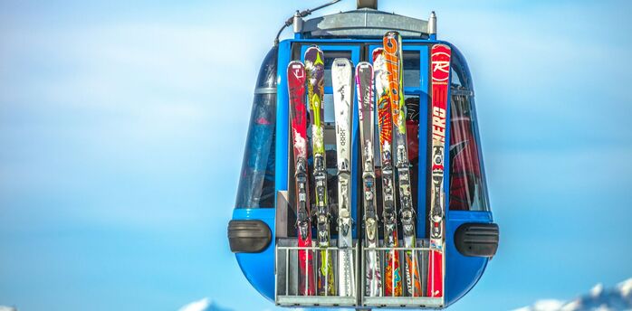 Ski gondola carrying skis with mountain peaks behind