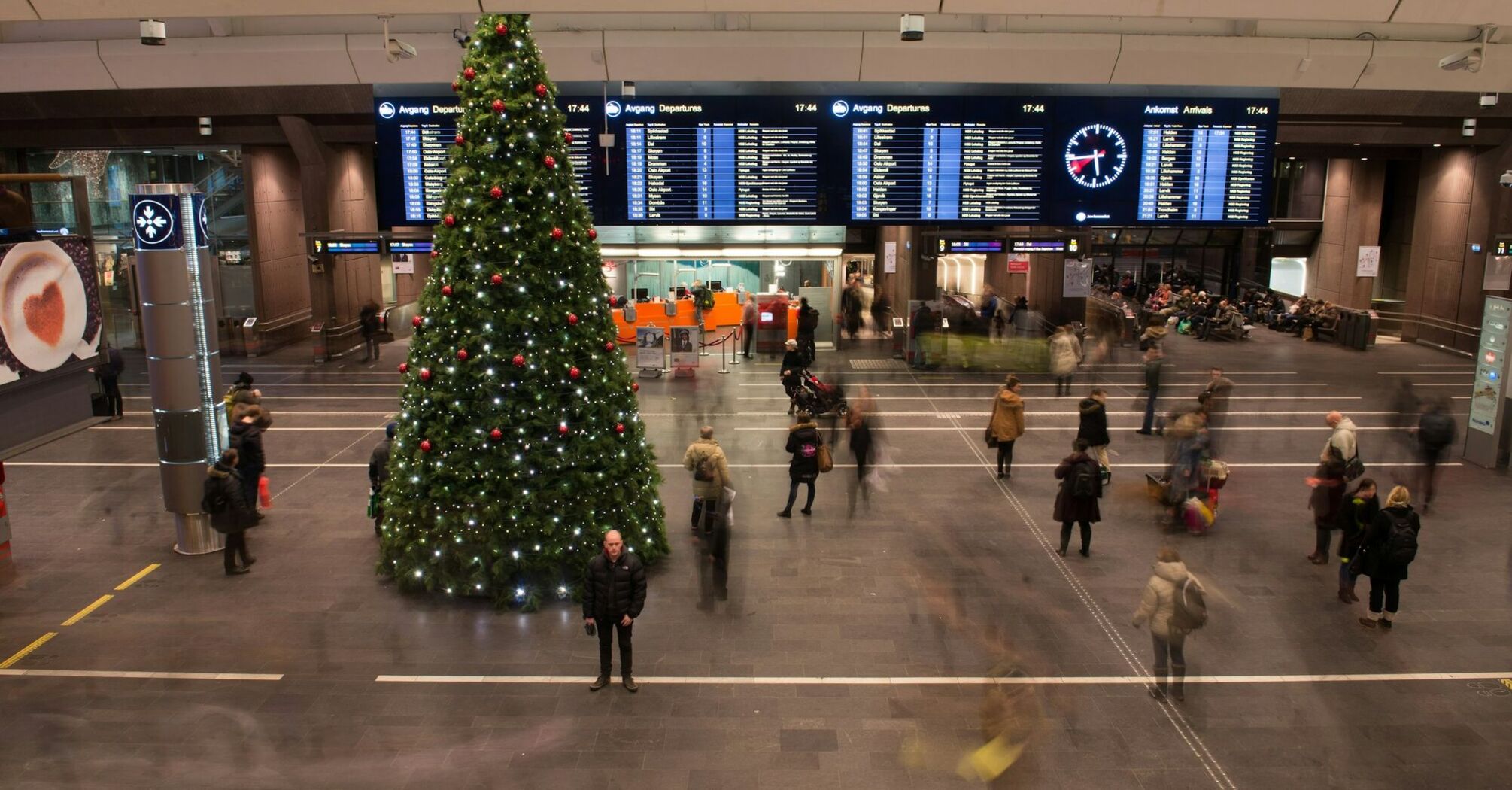 Christmas tree and passengers moving through a busy airport hall