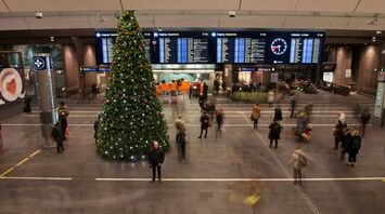 Christmas tree and passengers moving through a busy airport hall