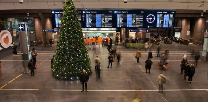 Christmas tree and passengers moving through a busy airport hall
