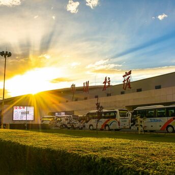 Exterior of a Chinese airport terminal at sunset with parked buses