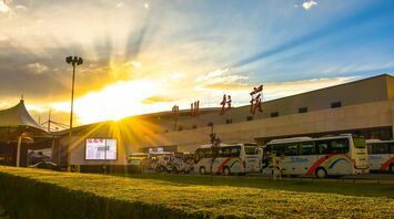Exterior of a Chinese airport terminal at sunset with parked buses