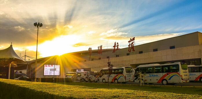 Exterior of a Chinese airport terminal at sunset with parked buses