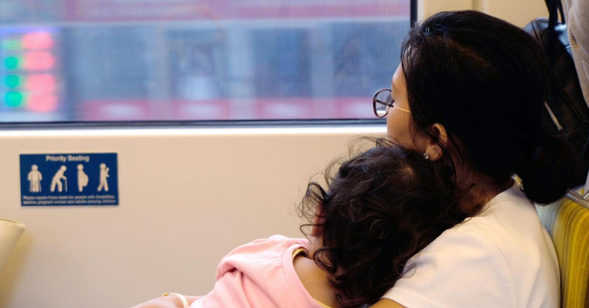 Mother and child resting on a train seat, looking out the window