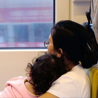 Mother and child resting on a train seat, looking out the window