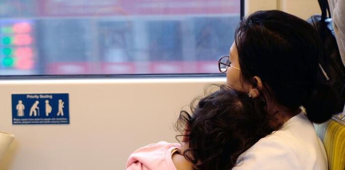 Mother and child resting on a train seat, looking out the window