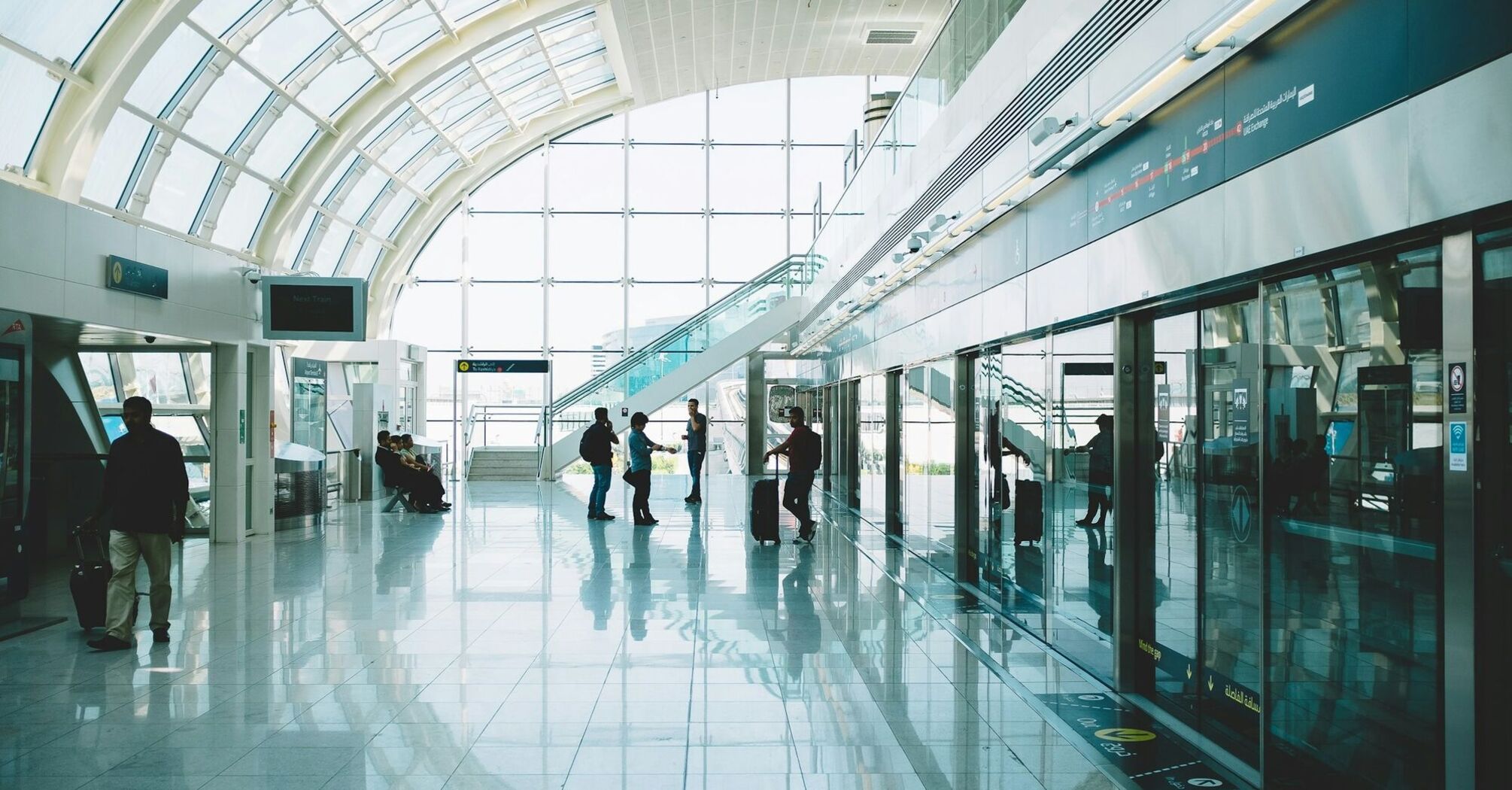 Interior view of Dubai International Airport’s Terminal 3 with passengers walking through bright glass corridors