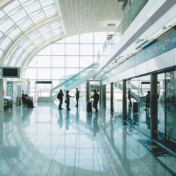 Interior view of Dubai International Airport’s Terminal 3 with passengers walking through bright glass corridors