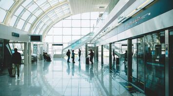 Interior view of Dubai International Airport’s Terminal 3 with passengers walking through bright glass corridors