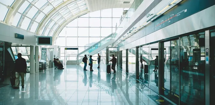 Interior view of Dubai International Airport’s Terminal 3 with passengers walking through bright glass corridors