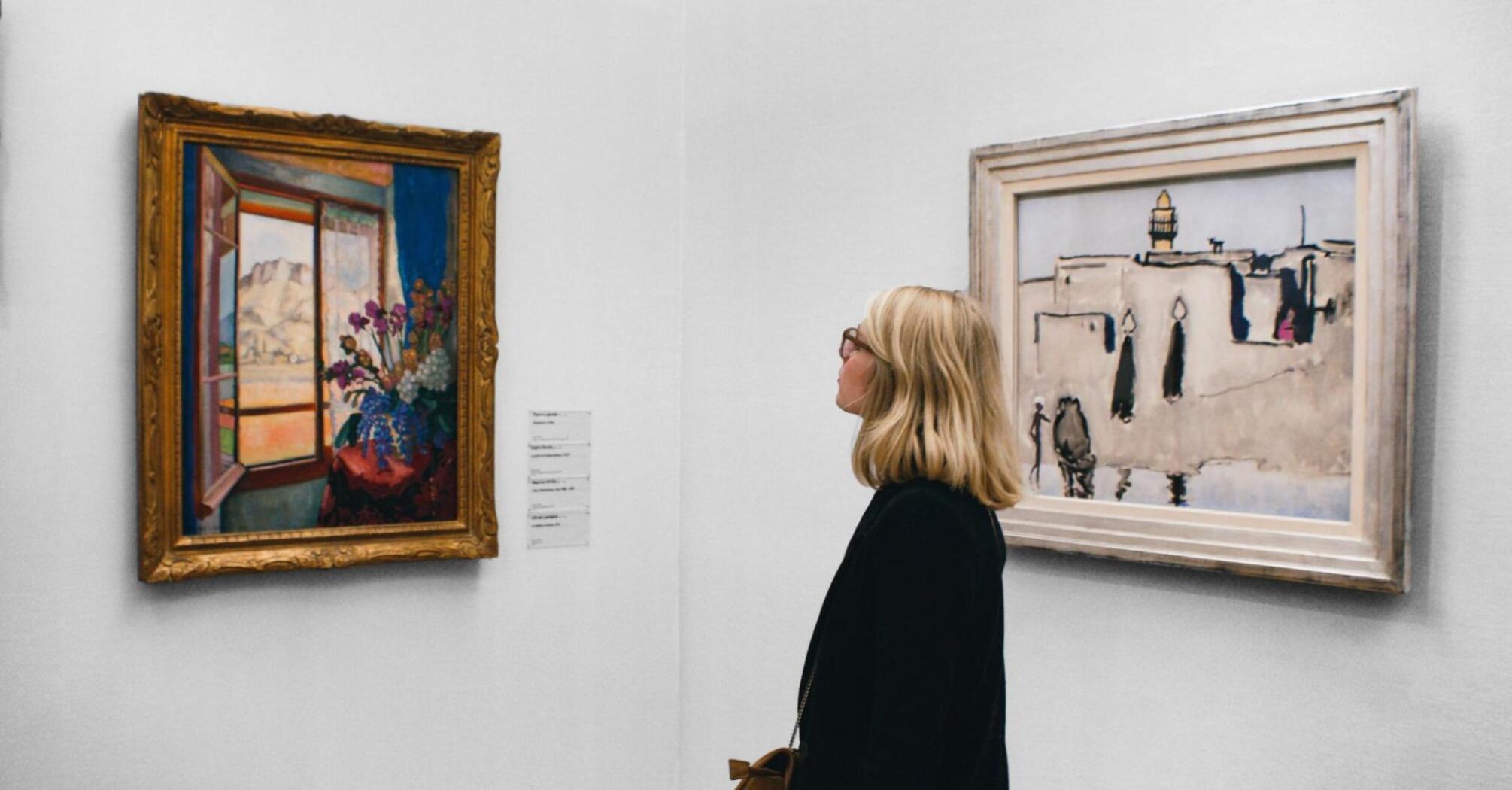Woman observing paintings at a UK art exhibition