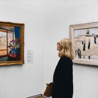 Woman observing paintings at a UK art exhibition