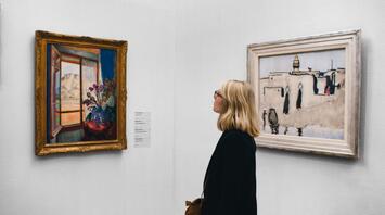 Woman observing paintings at a UK art exhibition
