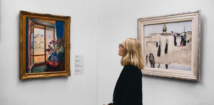 Woman observing paintings at a UK art exhibition