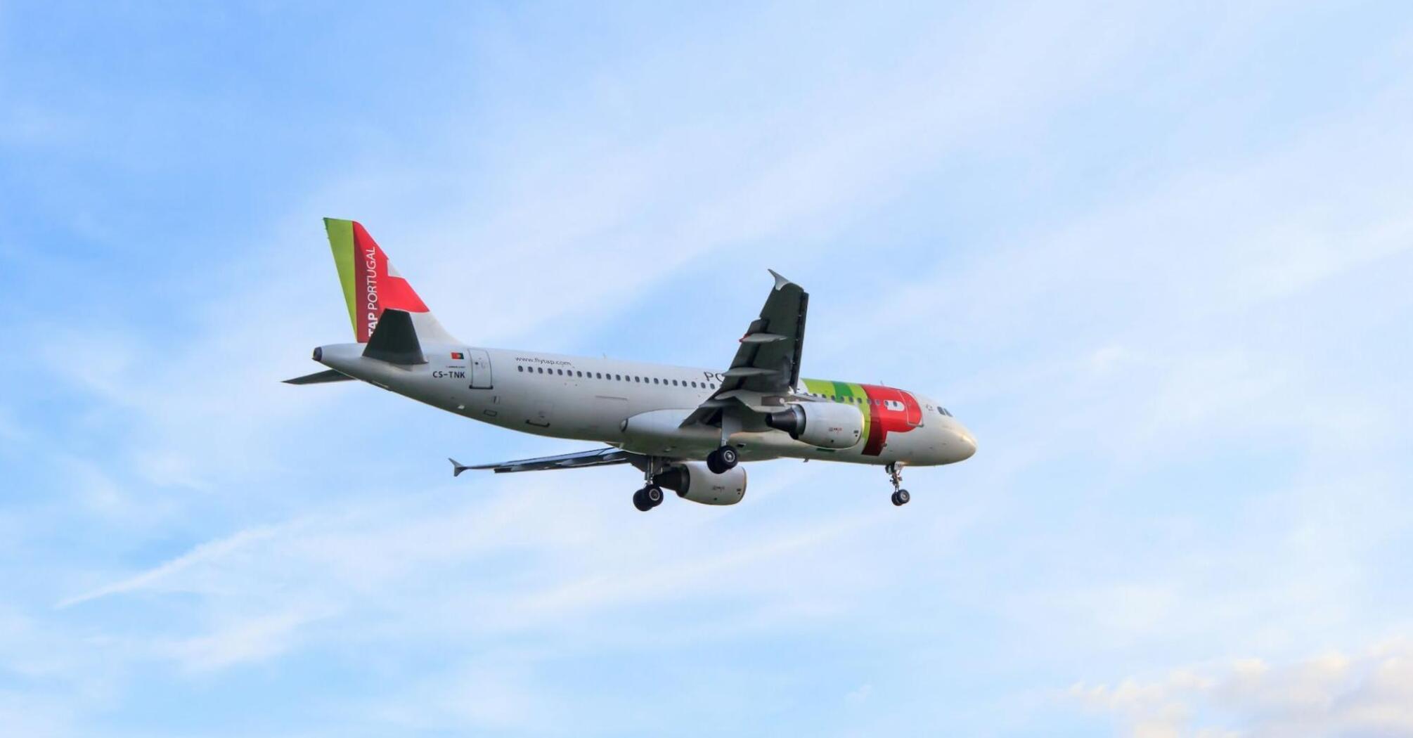 A TAP Air Portugal Airbus A320 flying through a clear sky