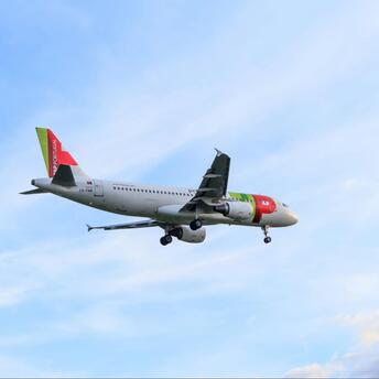 A TAP Air Portugal Airbus A320 flying through a clear sky