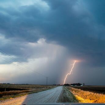 Lightning strikes under a dark storm cloud