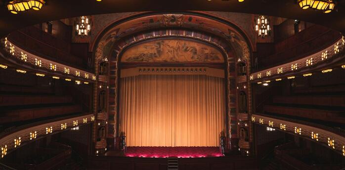 Interior of a historic UK theatre with golden curtains and ornate balconies