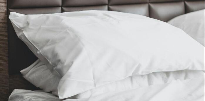 Neatly made hotel bed with white linens