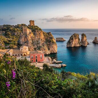 Coastal village and rocky cliffs in Sicily at sunset