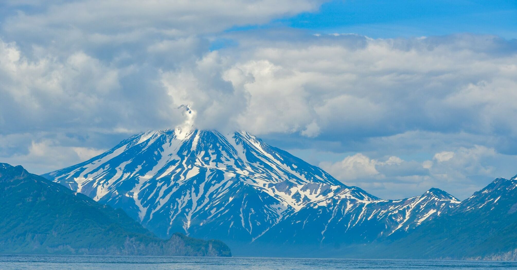 Snow-covered volcano on the Kamchatka Peninsula emitting a plume of smoke