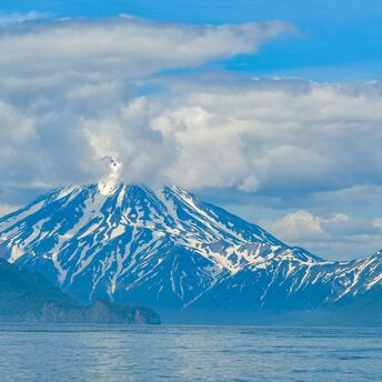 Snow-covered volcano on the Kamchatka Peninsula emitting a plume of smoke