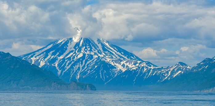 Snow-covered volcano on the Kamchatka Peninsula emitting a plume of smoke