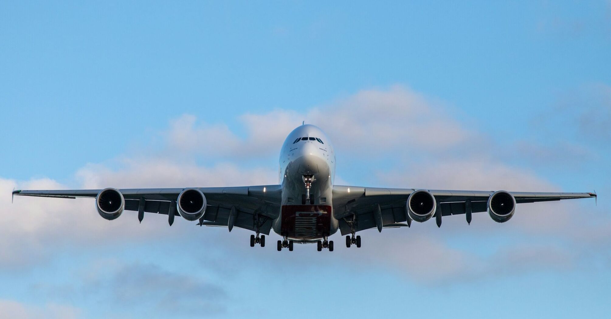 Front view of a large passenger airplane approaching for landing against a blue sky